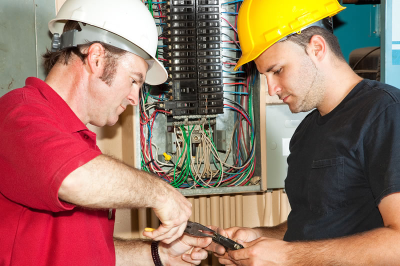 NJ Electrician Services - two electricians working at an electrical panel